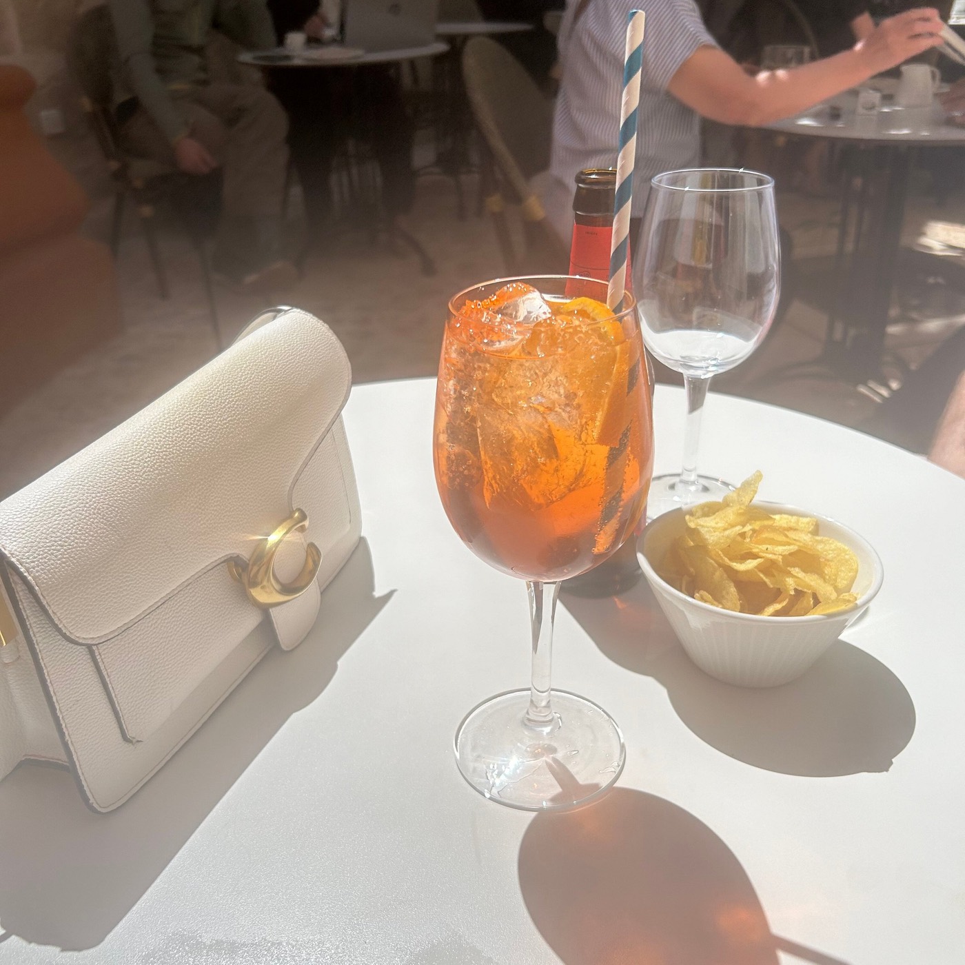 A spritz and a small plate laid on a white table in the courtyard