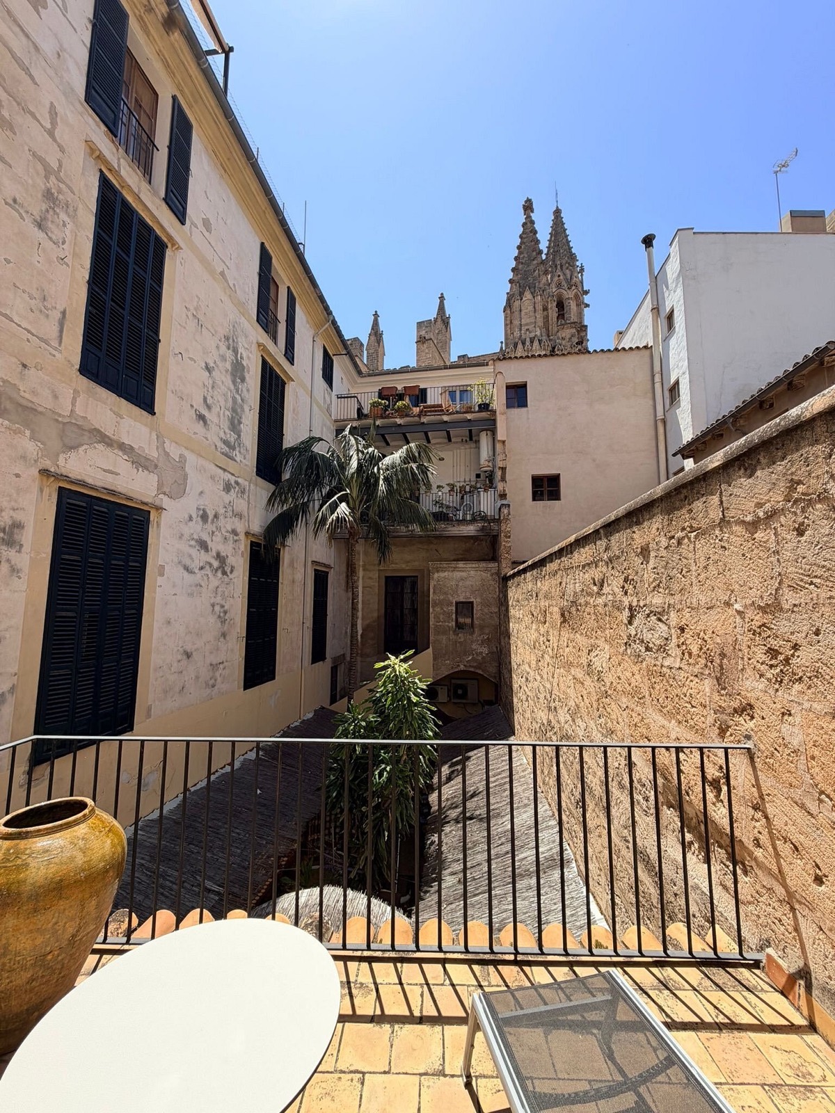 The courtyard with the bell-tower of Palma cathedral rising just above the stone wall