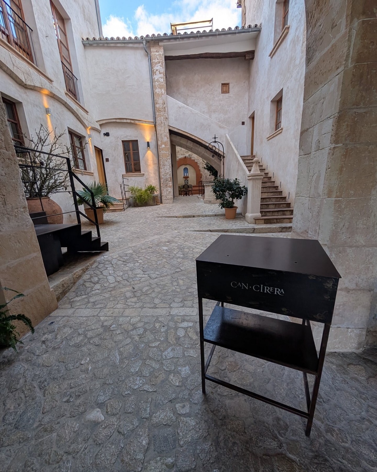 The cobbled and paved interior courtyard of the house, stone arches around it and a doorway leading deeper in