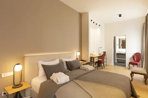 A deluxe double with a vaulted plasterwork ceiling, warm reading lights and a terracotta-toned accent wall, calm and well-proportioned
